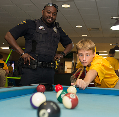 SIUE Police Officer Anthony Jones looks on with encouragement as Team Illinois Youth Police Camp cadet Elijah Duke, of Alton, plays pool.